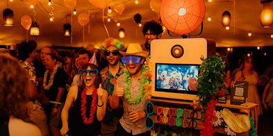 Bruidspaar en vrienden poseren bij photobooth met props en gepersonaliseerde fotostrip